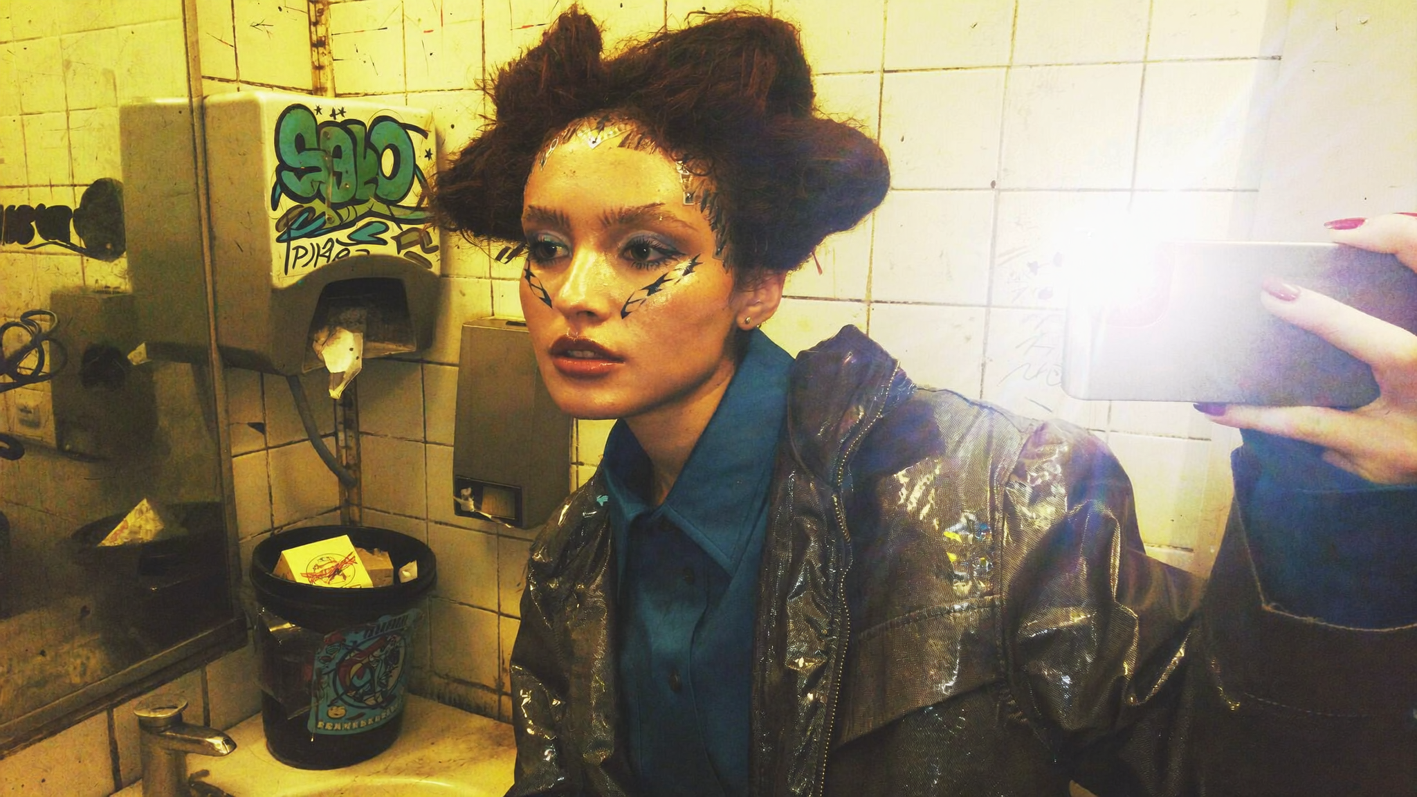 Backstage mirror — the inner studio is a bathroom wall with graffiti and a flash